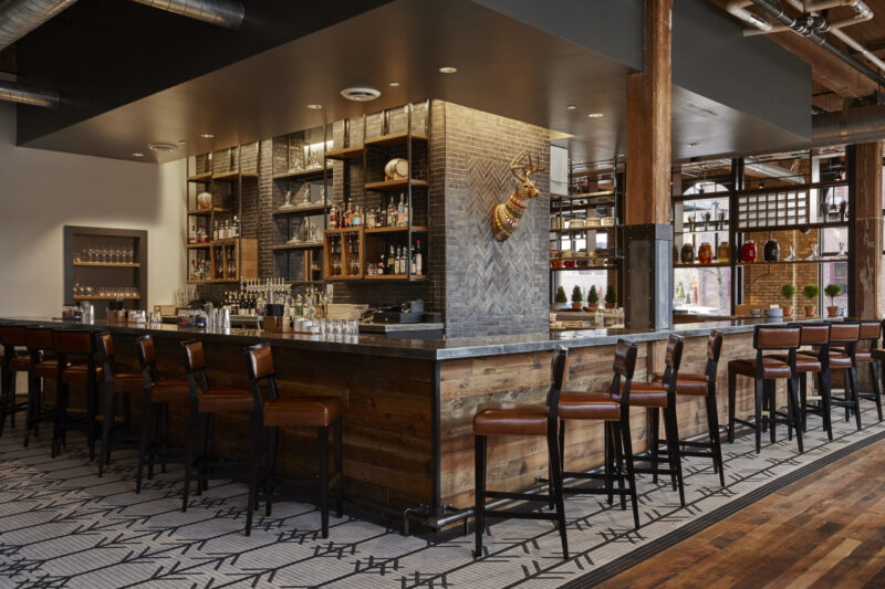 Cozy wooden bar with neatly lined up stools at our Minneapolis boutique hotel