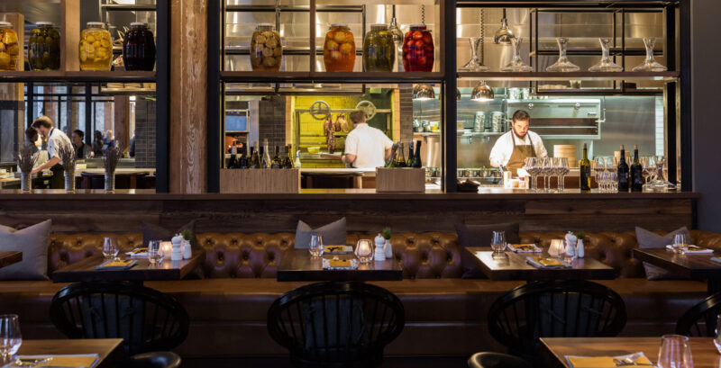 Neatly set tables overlooking the kitchen at Tullibee restaurant in Minneapolis