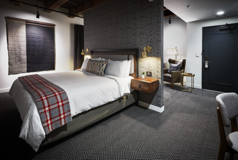 Bed with a plaid runner in a suite at our downtown hotel in Minneapolis, MN