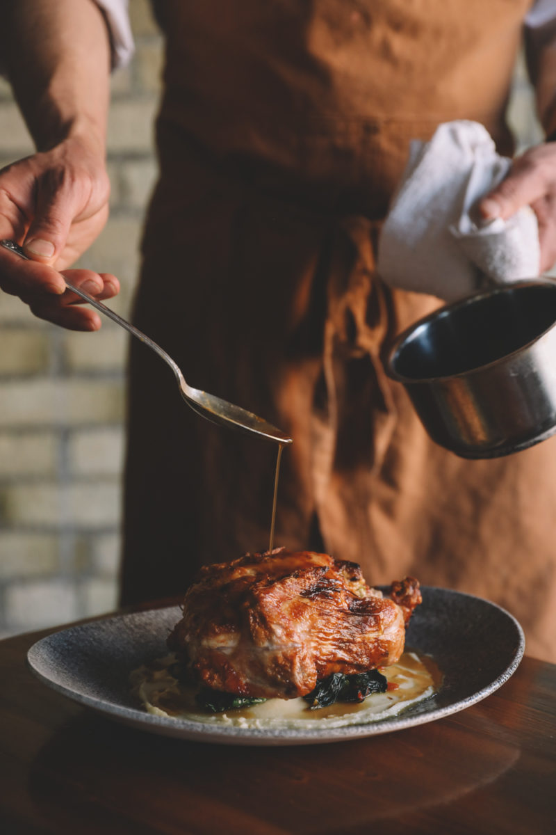 Chef pouring sauce onto a roasted chicken at our Minneapolis downtown hotel